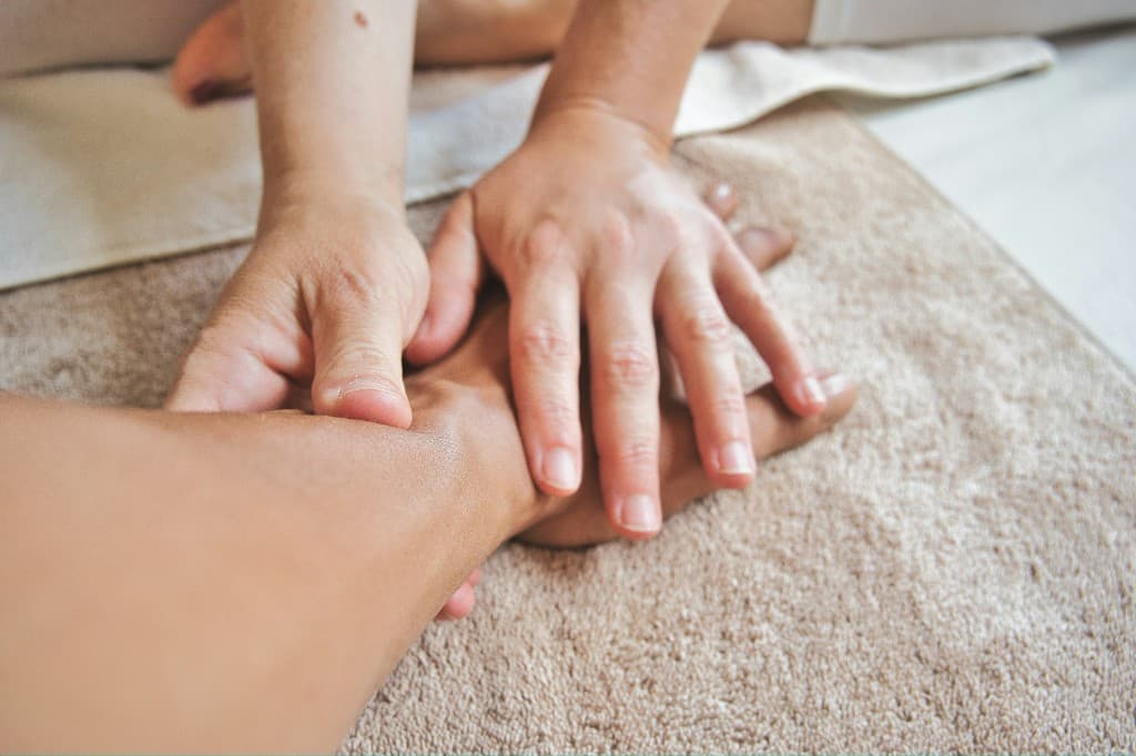 Massage therapist gently working through the muscles of a client's hand and wrist